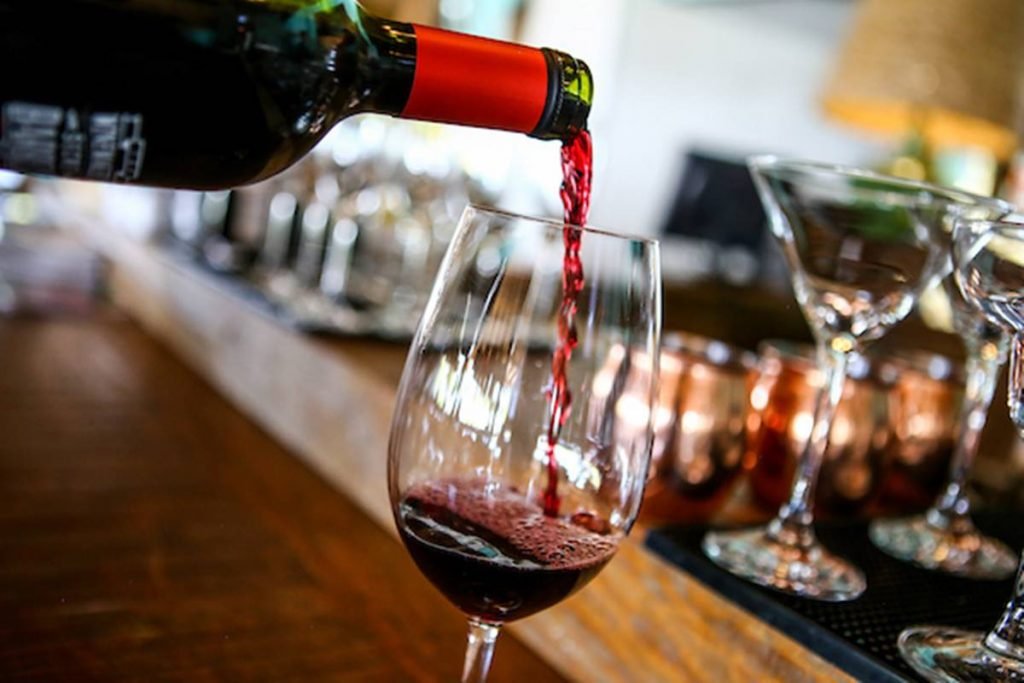 foto de garrafa de vinho derramando vinho em taça