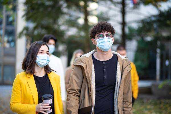 People walk and wear blue masks
