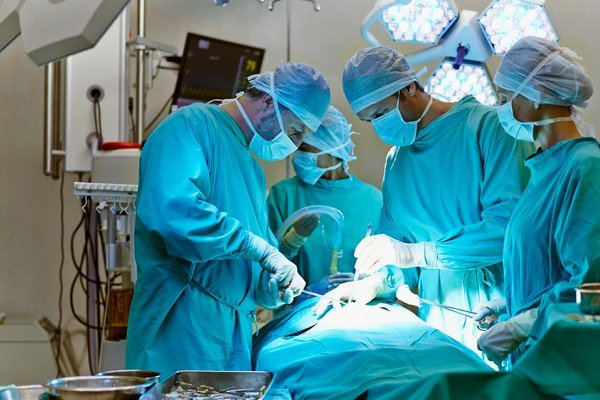 Sala de cirurgia com 3 médicos vestidos em uniforme hospitalar-Metrópoles