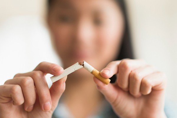 A woman holds a halved cigarette