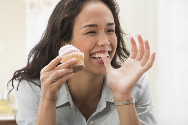 Woman eating candy.  She has dark hair and wears a light T-shirt -Metrópoles