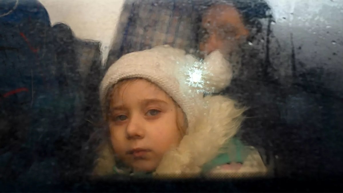menina olha pela janela com frio