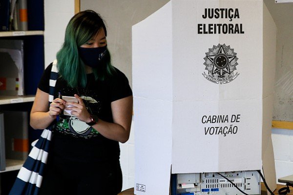 Mulher de cabelos coloridos vota em cabine-Metrópoles