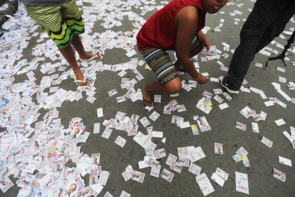 Homem agachado em meio aos papéis de propaganda eileitoral-Metrópoles