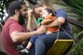 mulher e homem olham para criança em balanço
