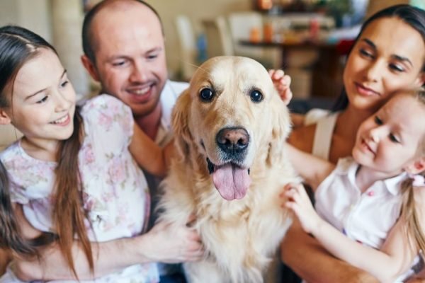Cachorro rodeado por uma família sorrindo