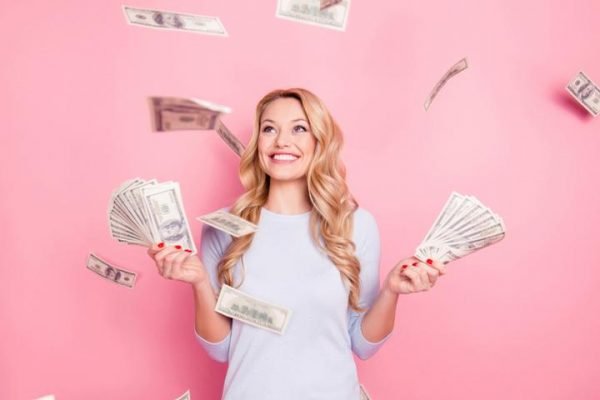 Mulher segurando notas de dinheiro em um fundo rosa