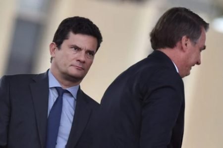 Bolsonaro e Sérgio Moro, ex-juiz e atual pré-candidato a Presidência da República. Eles usam terno escuro e camiseta branca- Metopoles