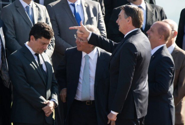 Bolsonaro e Sérgio Moro, ex-juiz e atual pré-candidato à Presidência da República.  Eles usam terno escuro e camiseta branca- Metopoles