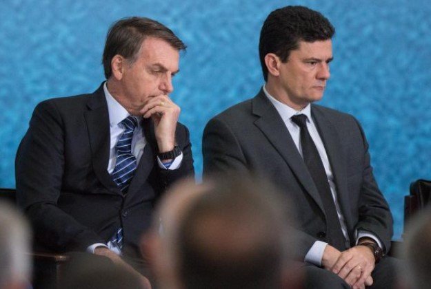 Bolsonaro e Sérgio Moro, ex-juiz e atual pré-candidato à Presidência da República.  Eles usam terno escuro e camiseta branca- Metopoles