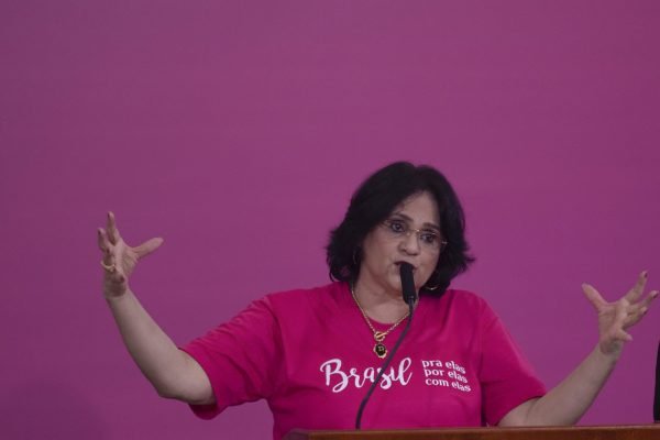 Ministra Damares Alves discursa em cerimônia de comemoração do Dia da Mulher no Palácio do Planalto. Ela acena para a plateia e usa rosa - Metrópoles
