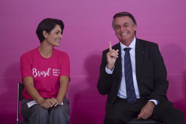 Michelle e Jair Bolsonaro em cerimônia de comemoração do Dia da Mulher no Palácio do Planalto. Eles sorriem um para o outro - Metrópoles