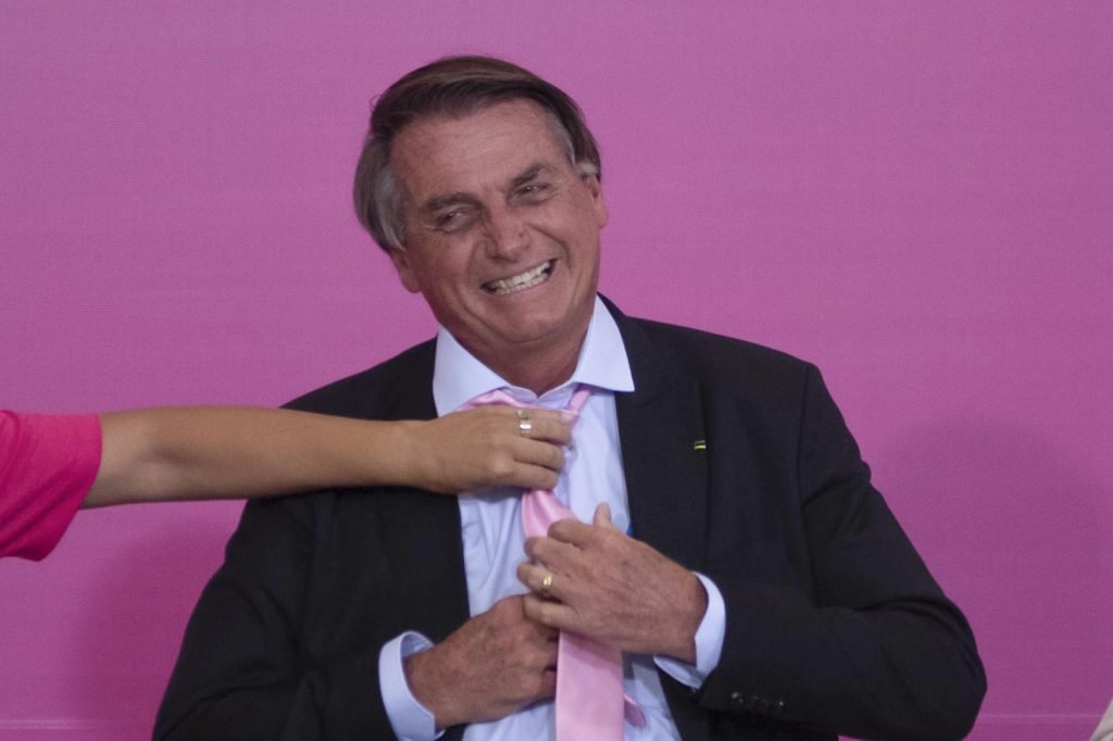 A primeira dama Michelle Bolsonaro ajeita a gravata do presidente Jair Bolsonaro em cerimônia de comemoração do Dia da Mulher no Palácio do Planalto - Metrópoles