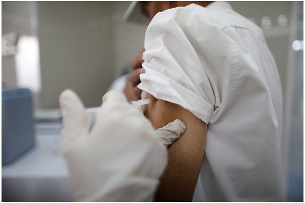 Homem de camiseta branca toma vacina no braço-Metrópoles