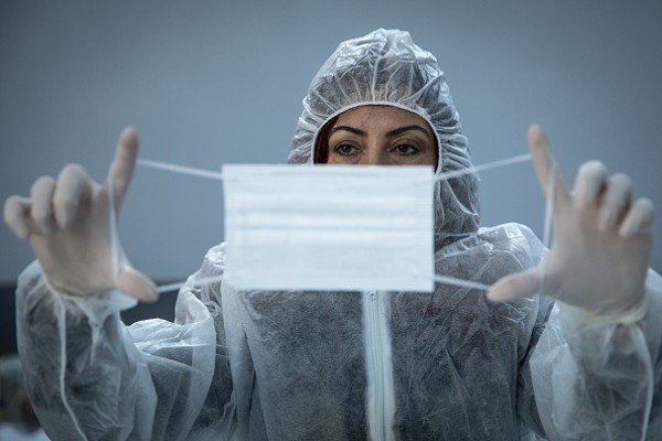 Mulher usando equipamento estica uma máscara nas mãos-Metrópoles