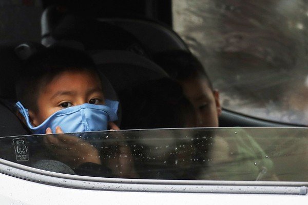 Criança dentro de carro segura máscara no rosto com as mãos-Metrópoles