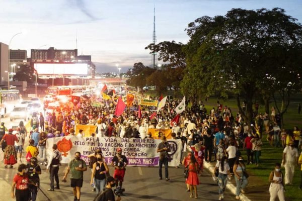 Em manifestação contra o machismo, racismo e lgbtfobia na Esplanada, em Brasília, mulheres e homens caminham com cartazes pela avenida no anoitecer - Metrópoles