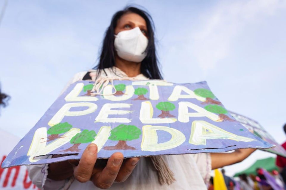 Em manifestação contra o machismo, racismo e lgbtfobia na Esplanada, mulher levanta cartaz que diz