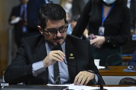 O senador capixaba Marcos do Val discursa na Comissão de Constituição e Justiça, folheando papel e segurando microfone - Metrópoles