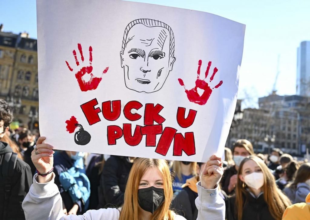 Em manifestação em Hessen, Alemanha, pessoas levantam cartazes em reúpido à Rússia. Em um deles, está escrito 