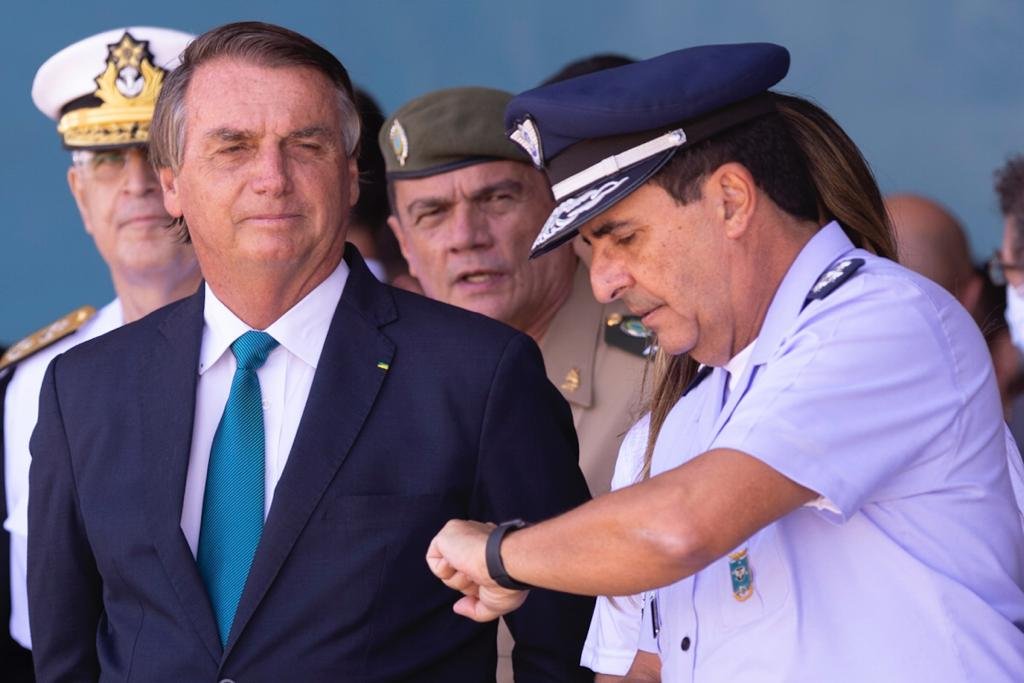 O presidente Bolsonaro conversa com o comandante da Aeuronáutica Carlos Alberto Baptista Junior enquanto aguardam o avião com resgatados pousar - Metrópoles