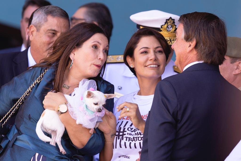 O presidente Bolsonaro conversa com a deputada federal Bia Kicis (DF-PSL), que segura um cachorro, ao lado do ministro Braga Netto e a primeira-dama Michelle Bolsonaro enquanto aguardam o desembarque dos resgatados da guerra da Ucrânia - Metrópoles