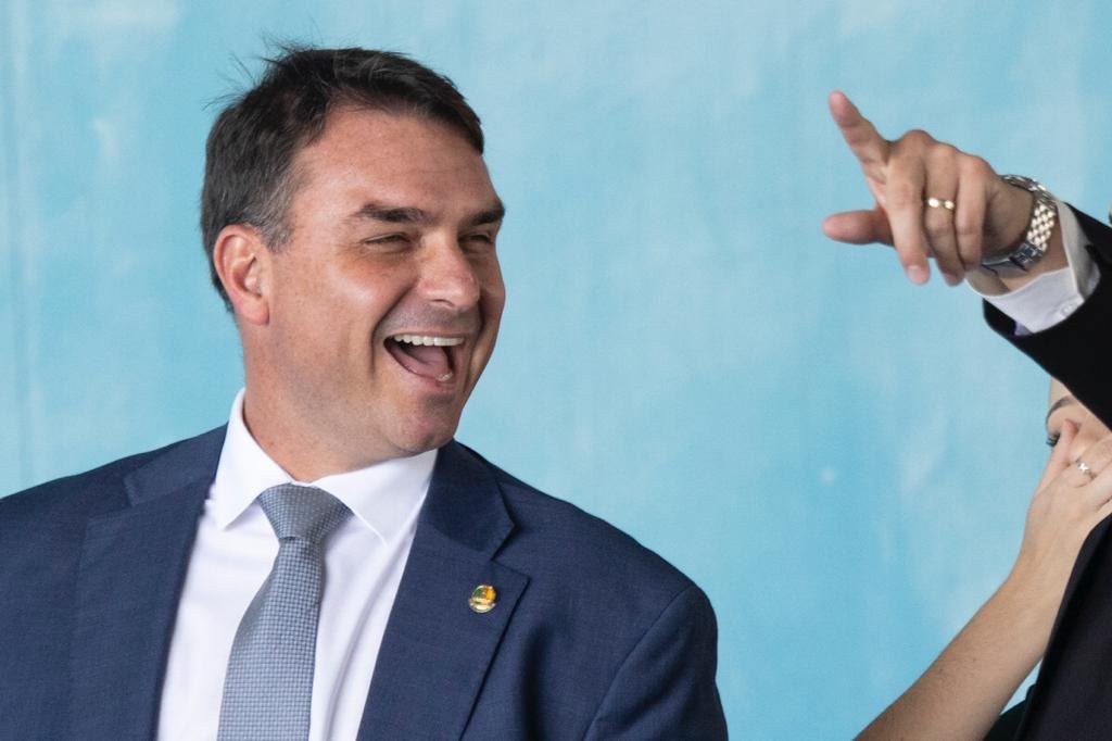 O senador Flávio Bolsonaro ri enquanto aguarda o desembarque dos resgatados da guerra da Ucrânia - Metrópoles