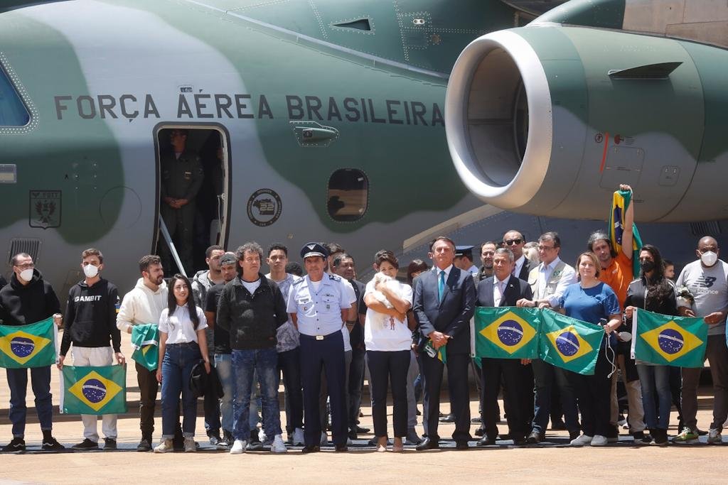Resgatados da guerra da Ucrânia, vindos da Polônia, e desembarcam em base aérea em Brasília e posam com o presidente Bolsonaro e autoridades segurando a bandeira do Brasil - Metrópoles