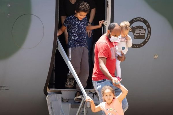 Um dos resgatados da guerra da Ucrânia, vindos da Polônia, desce com as duas filhas do avião da FAB- Metrópoles