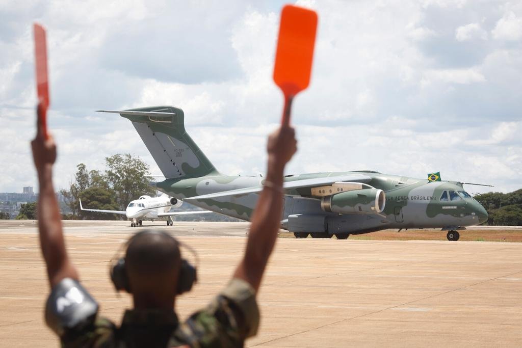 Aeronave da FAB que trouxe resgatados da guerra da Ucrânia, vindos da Polônia, manobrando em pista de base aérea em Brasília enquanto militar dá instruções - Metrópoles