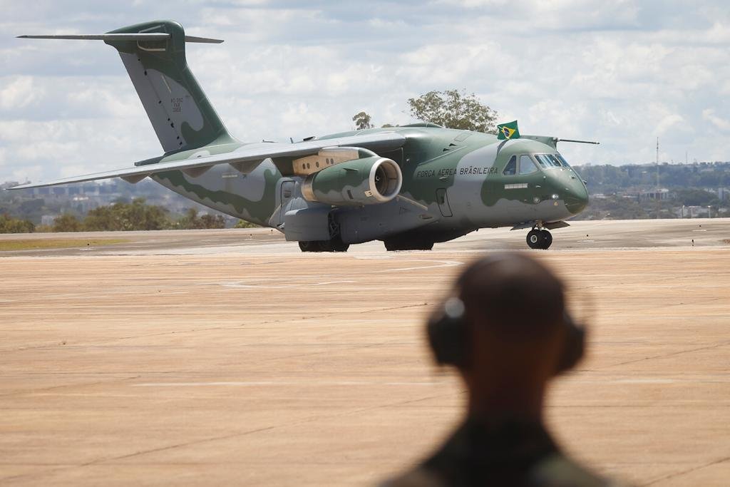 Aeronave da FAB que trouxe resgatados da guerra da Ucrânia, vindos da Polônia, manobrando em pista de base aérea em Brasília enquanto militar dá instruções - Metrópoles
