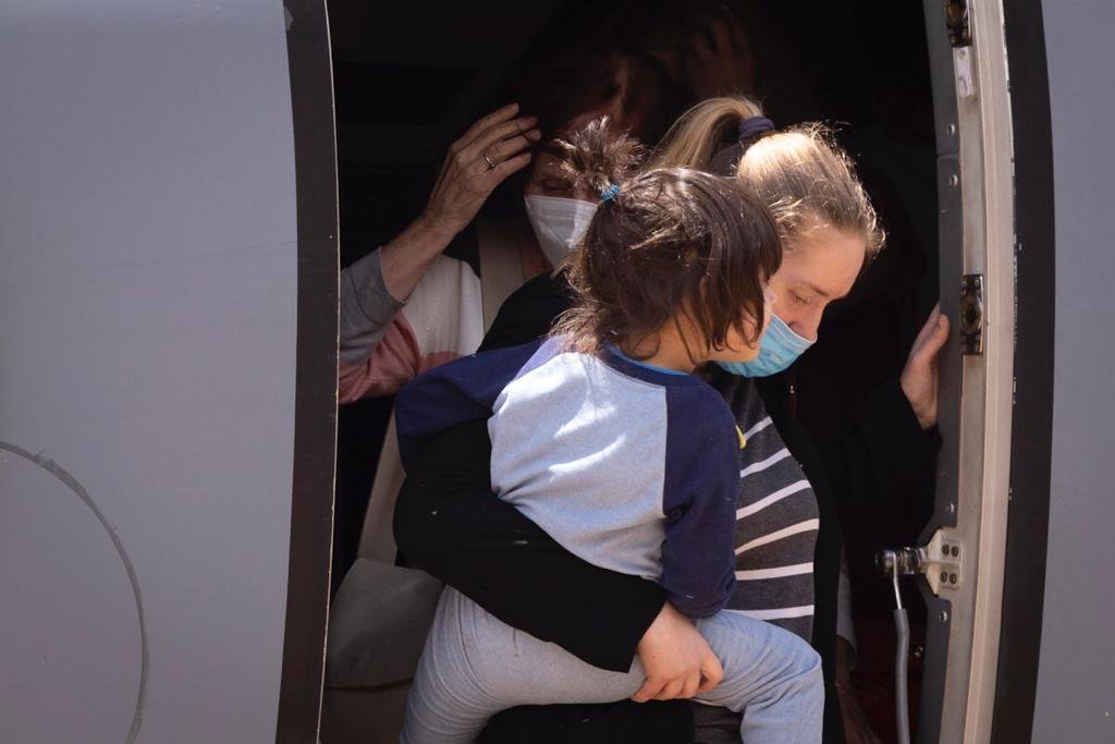 Mãe desce com filha no colo de aeronave da FAB que trouxe resgatados da guerra da Ucrânia, vindos da Polônia - Metrópoles