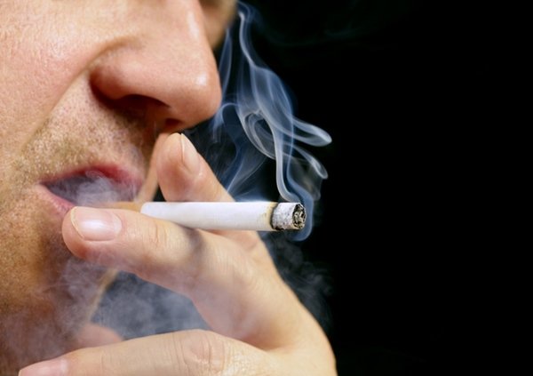 Pessoa com um cigarro na boca fumado - Metrópoles