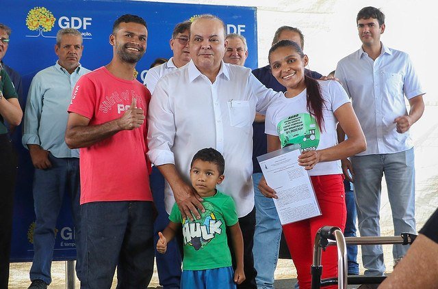 Ibaneis Rocha, de camisa branca, abraça família durante entrega de contratos de concessão de uso em regime probatório de áreas rurais