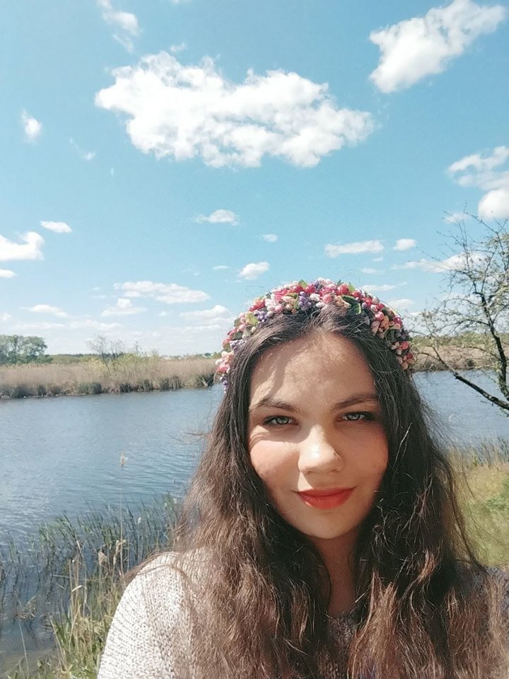 Menina com coroa de flores em frente a lago