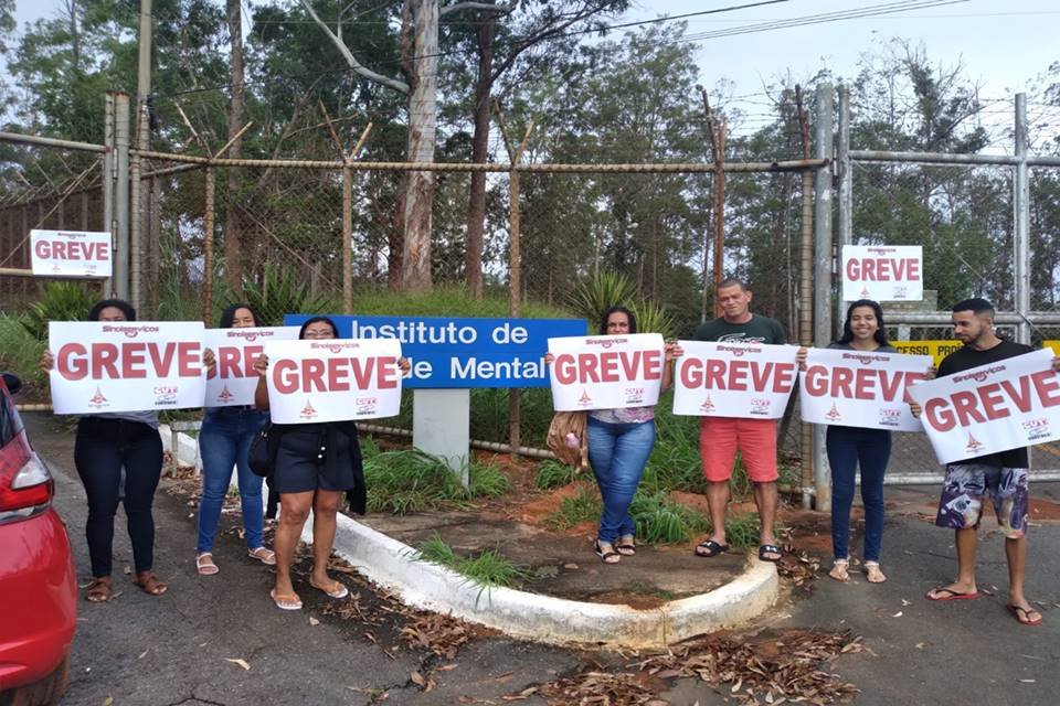 Pessoas seguram placa de greve