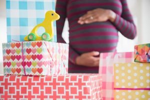mulher grávida com mão na barriga enquanto observa caixas de presentes