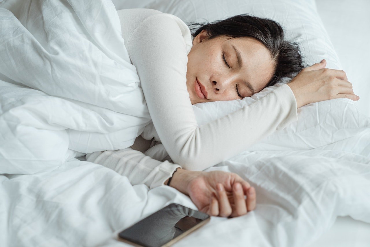 Mulher dormindo com um celular - Metrópoles