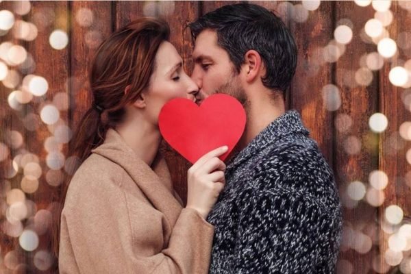 Casal se beijando com coração vermelho na frente