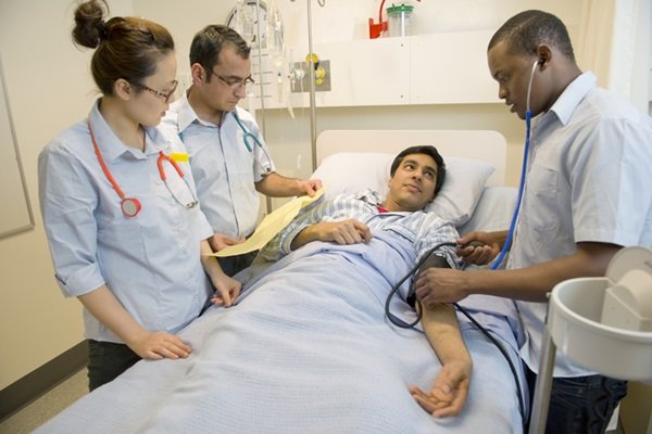 Person lying on hospital gurney with people dressed as healthcare professionals around him - Metropolis