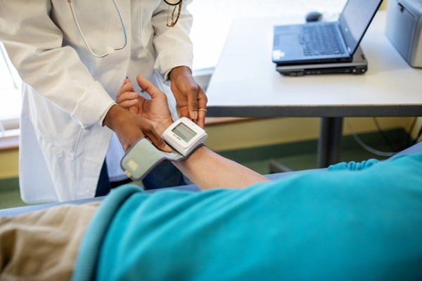 Person measuring blood pressure with another person wearing a white coat - Metrópoles