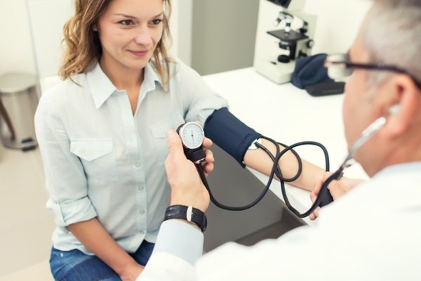 Woman checking blood pressure with another person wearing a white coat - Metrópoles