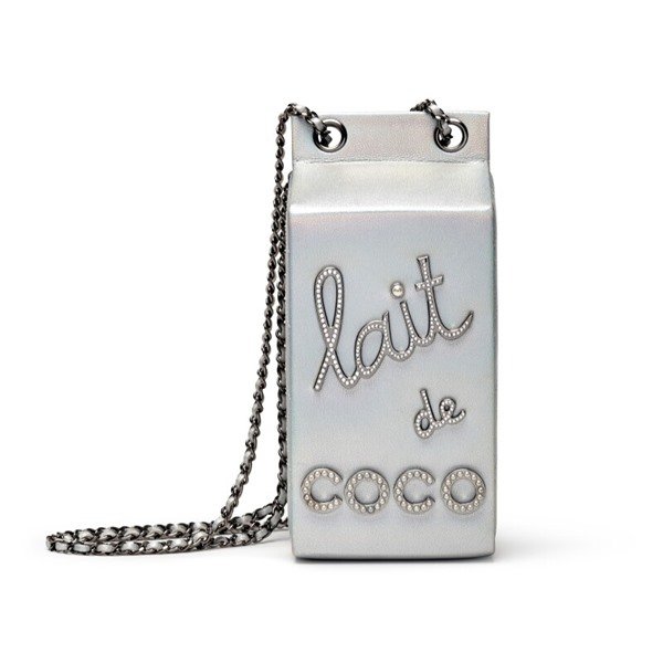 Bolsa da marca Chanel que imita uma caixa de leite. Ela é branca e possui escritos e corrente em prata.