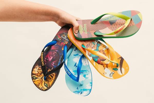 Mão segurando sandálias Havaianas estampadas