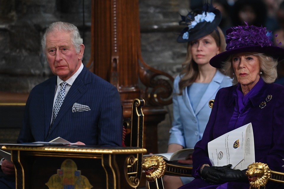 Foto colorida. Príncipe Charles e Kate Middleton estão sentados