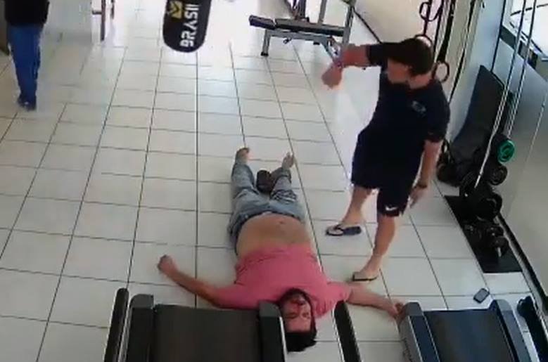 Homem de camisa rosa deitado no chão e homem de preto em cima