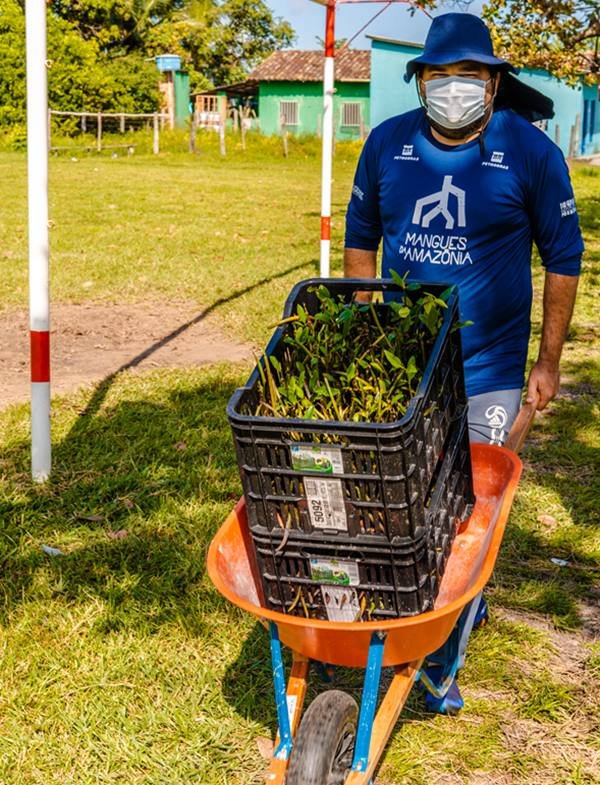 homem com camisa azul carrega um carrinho de mão