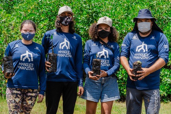 pessoas posam para foto segurando mudas de plantas