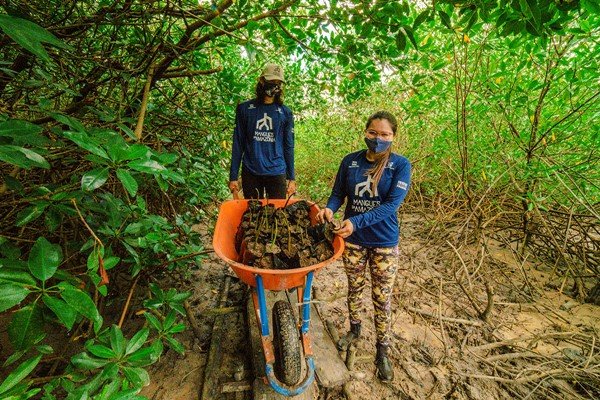 duas mulheres de camisa azul posam para uma foto dentro de uma floresta