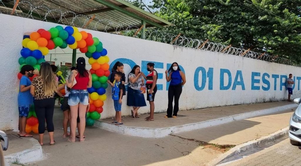 Balões e pessoas em frente a muro de escola